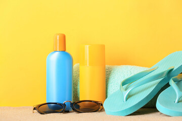 Beach accessories with sunscreen cream on color background