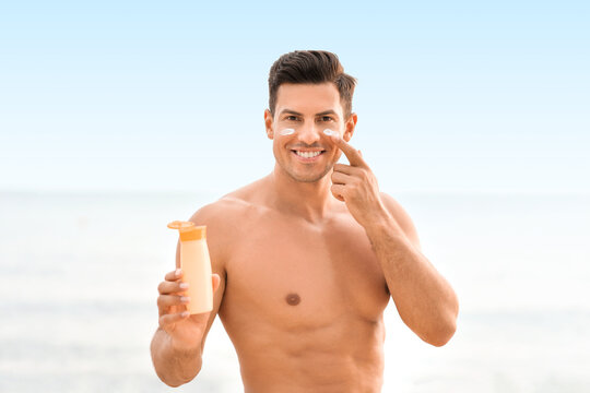 Young Man Applying Sunscreen Cream On Sea Beach