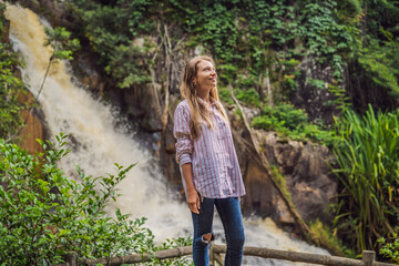 Young woman standing near a waterfall in forest. Male hiker in the nature