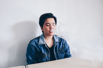 Asian beautiful short hair girl wear jeans jacket is smoking electronic cigarette or vaping vape on...