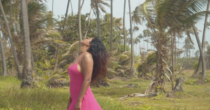 A sexy woman lets her hair flow in the wind at this epic Caribbean location with coconut trees in the background
