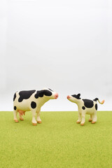 牛の親子の粘土人形　立体　芝生の背景イメージ