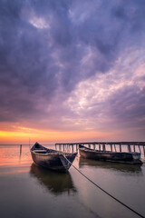 Beautiful sunrise or sunset on a lake with wooden fisherman boats