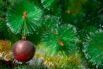 On the green Christmas tree hangs a large brown and gold Christmas ball: happy new year and Christmas! Close up. Christmas decor