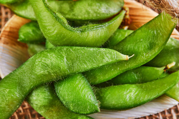 Edamame or soybeans in a wooden plate on a brown sackcloth