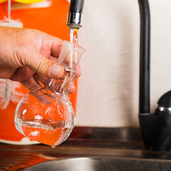 A man pours tap water into a glass flask.