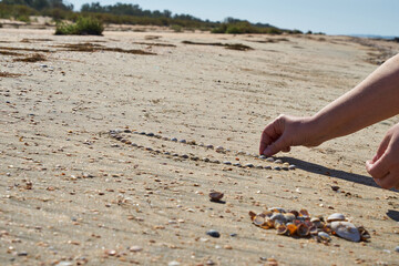 Girl lays out a drawing in the sand.