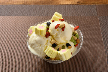 side view bowl of vanilla flavor ice cream sundae starts melting with marshmallows and various nuts