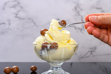 man eating bowl of vanilla flavor ice cream sundae with chocolate candy