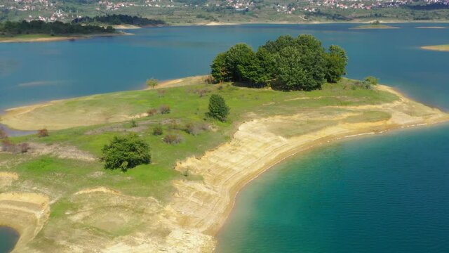 Bosnia and Herzegovina Rama Lake island with group of trees and eroded shoreline, Aerial dolly left shot