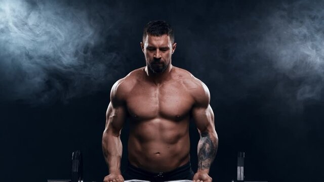 Fit and sporty bodybuilder over black background. Bodybuilder training using barbell. Sport and fitness.