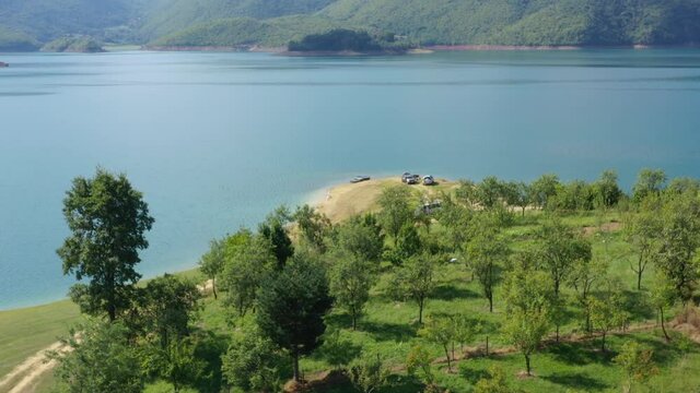 Rama Lake in Bosnia and Herzegovina with Cars parked near shore making a camp site, Aerial dolly in shot