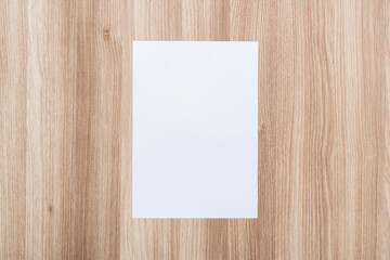 White blank sheet of paper on a wooden table.