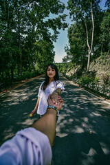 Cropped Image Of Man Holding Hands With Girlfriend Standing On Road In Forest