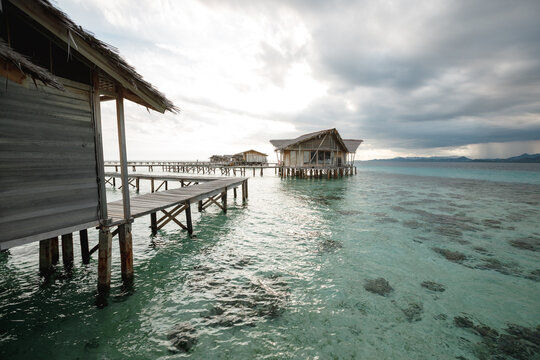Pier leading to wooden overwater bungalows that sit above crystal clear blue water, vacation on the tropical island