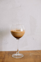 Glass of trendy coffee drink with milk against concrete wall. Dalgona coffee.