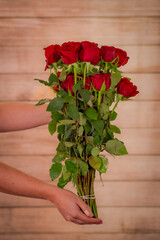 Fototapeta na wymiar Women hand holding a bouquet of Hearts Garden roses variety, studio shot, red flowers