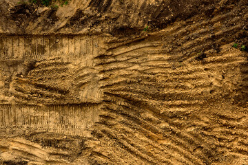 Embossed trail excavator tracks on the wet sand.