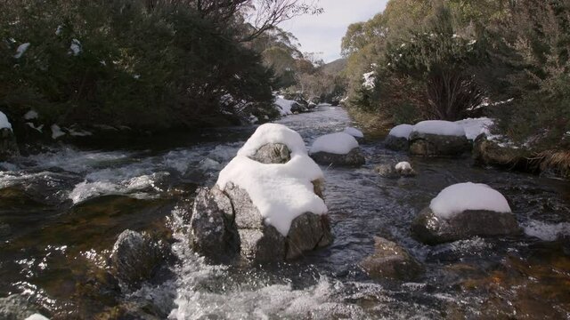 Looking downstream as freezing river water rages past snow covered rocks in the Australian mountains