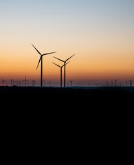 Obraz premium Black Silhouette of windturbines energy generator on amazing sunset at a wind farm in germany