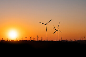 Obraz premium Black Silhouette of windturbines energy generator on amazing sunset at a wind farm in germany