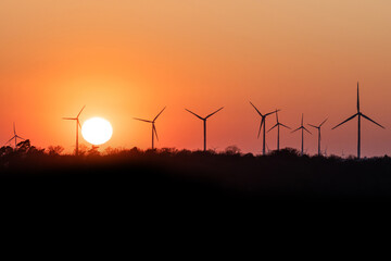 Fototapeta premium Black Silhouette of windturbines energy generator on amazing sunset at a wind farm in germany