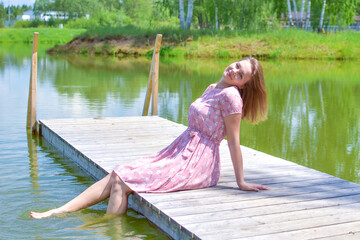 rest on a pond in the summer, a woman sits on a wooden bridge on the lake
