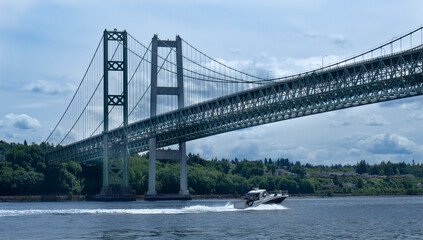 Fast cruising boat transiting underneath the Tacoma Narrows Bridge