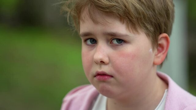 portrait of a plump sad girl with short blond hair on a green lawn