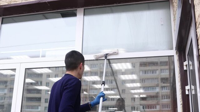 a professional window cleaner soaps and squeegies a window clean, male cleaning worker.