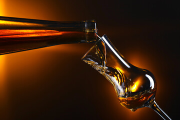 Pouring alcohol into a glass on dark background