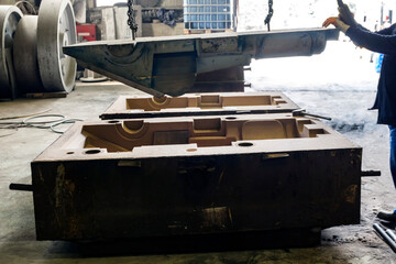 The worker is preparing sand mold for steel casting. The mold cavities and gate system are created by compacting the sand around models called patterns, by carving directly into the sand.