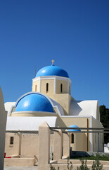 Beautiful white churches of the island of Santorini in Greece with white walls and blue domed roof and bright blue sky behind