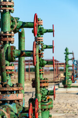 Petroleum well wellhead equipment. Hand valve with handwheel on the flow line. Oilfield site. Oil, gas industry concept. Industrial site background. Production oil. Multiple check valve gate armature.