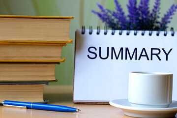 SUMMARY - word in a notebook on a background of old books with pen and white cup
