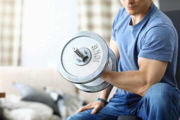 Athletic man shakes his biceps with dumbbell in his hands. Healthy lifestyle concept