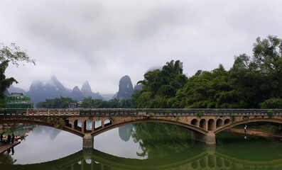 Reflections of a bridge and karst mountains in Yangshuo, China