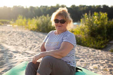 Fototapeta na wymiar happy senior beautiful woman sitting on a sand in summer beach