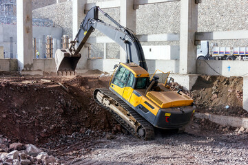 The excavator is climbing from soil pile. Excavators are also called diggers. Excavators (hydraulic) are heavy construction equipment consisting of a boom, dipper, bucket and cab.
