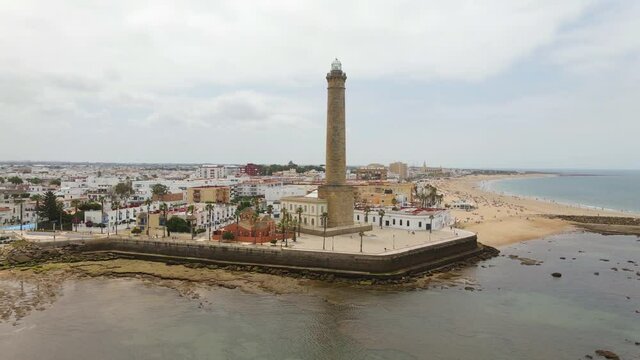 The high lighthouse of Chipiona on the Atlantic in Andalusia. The drone flies a semicircle with a view of the city and the coastal landscape in the north.