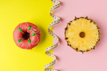 a doughnut and a circle of fresh pineapple on a yellow-pink background. the concept of choosing the right food.
