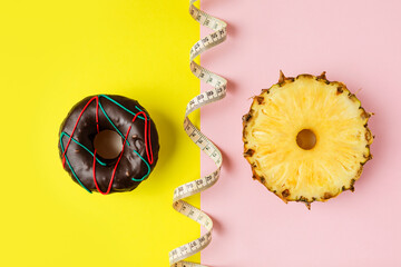 a doughnut and a circle of fresh pineapple on a yellow-pink background. the concept of choosing the...