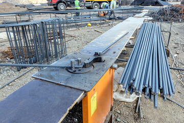 The worker is bending rebars with rebar bending machine in the site. The most common type of rebar is carbon steel, typically consisting of hot-rolled round bars with deformation patterns.