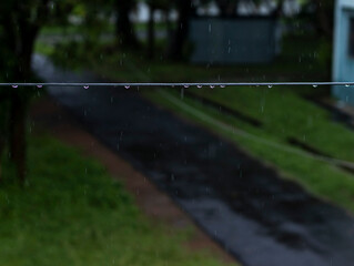 selective focus on the water droplets hanging from the cable in a dark wet rainy day