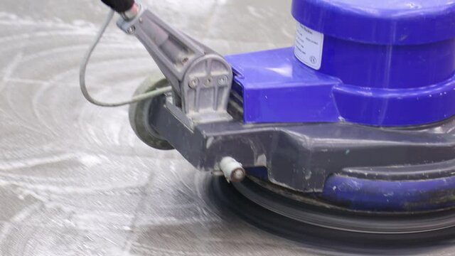 the cleaner washes a pier with a professional polisher machine. Cleaning floor in office building lobby
