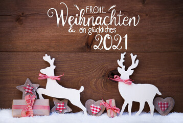 German Calligraphy Frohe Weihnachten Und Ein Glueckliches 2021 Mean Merry Christmas And Happy 2021. Wooden Christmas Ornament Like Present, Heart And Wooden Deer. Wooden Background With Snow