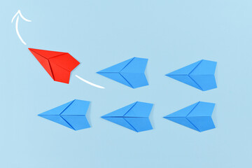 Red paper airplane flying out of line leading blue airplanes. Concept for new business strategies, leadership, discovery, and different thinking