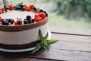 Mousse cake with berries on a wooden table. Chocolate cream cake with currants and cherries. Berry cake for birthday, wedding and other holidays.