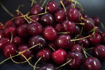 Red fresh cherries on a black background. Drop of water. Close up. The concept of freshness.