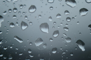 Rain drops on window glasses surface with cloudy background . Natural Pattern of raindrops on...